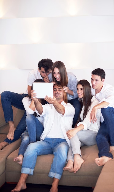 grupa przyjaciół robiących zdjęcia selfie z tabletem w nowoczesnym domu w pomieszczeniu