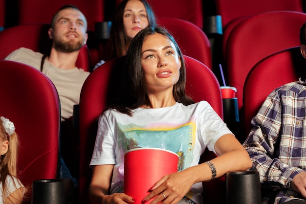 Grupa przyjaciół siedząc w kinie z popcornem i napojami