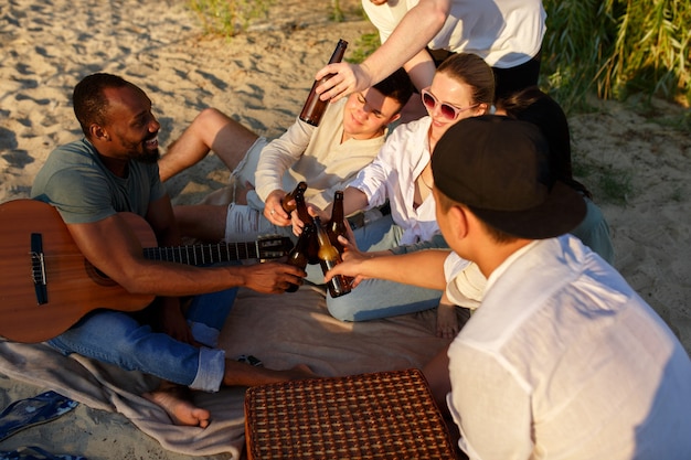 Grupa Przyjaciół Stukająca Się Szklankami Piwa Podczas Pikniku Na Plaży?