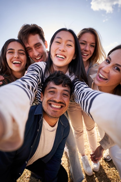 Zdjęcie grupa różnorodnych szczęśliwych młodych przyjaciół robiących wspólnie selfie, uśmiechając się do kamery.