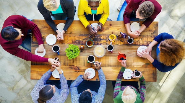 Zdjęcie grupa różnych ludzi siedzi wokół drewnianego stołu, rozmawia i pije kawę i herbatę