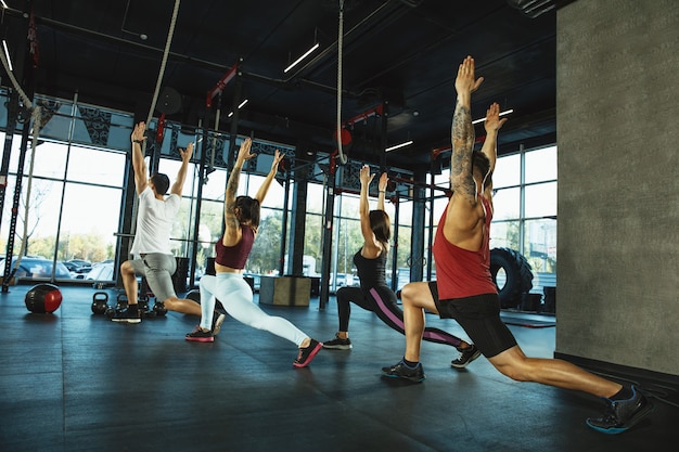 Grupa sportowców mięśni robi trening na siłowni. Gimnastyka, trening, elastyczność treningu fitness. Aktywny i zdrowy tryb życia, młodość, kulturystyka. Trening w wypadach i ćwiczenia rozciągające