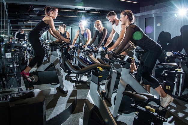 Grupa sportowców trenujących razem na rowerach sportowych w siłowni