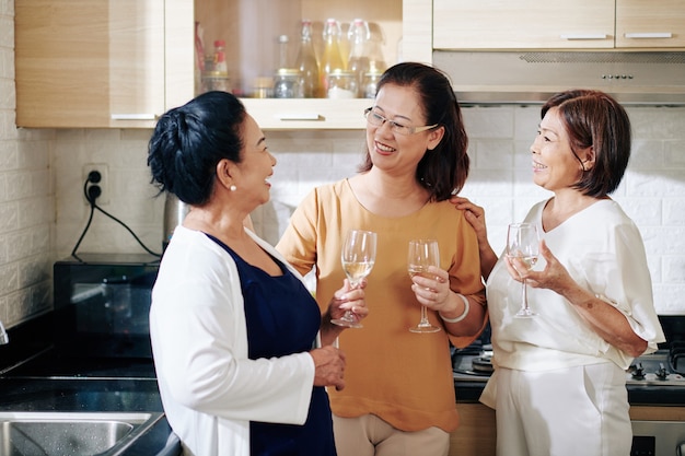 Grupa starszych Azjatek pijących szampana w kuchni na imprezie domowej