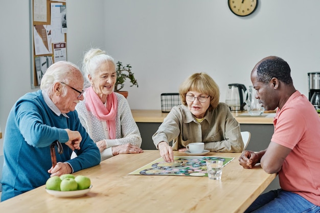 Grupa starszych osób siedzących przy stole i grających razem w gry planszowe