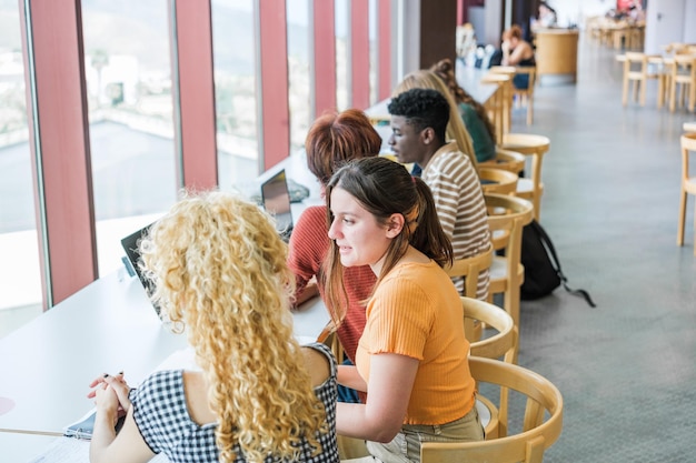 Grupa studentów z różnych środowisk etnicznych uczących się razem w bibliotece uniwersyteckiej