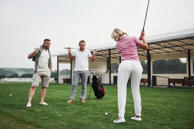 Zdjęcie grupa stylowych przyjaciół na polu golfowym uczy się grać w nową grę