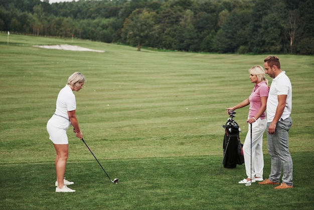 Zdjęcie grupa stylowych przyjaciół na polu golfowym uczy się grać w nową grę