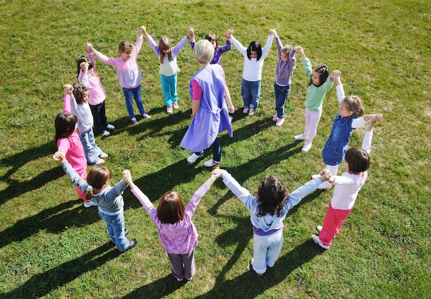 grupa szczęśliwych dzieci bawi się i bawi w przedszkolu koncepcja edukacji przedszkolnej na świeżym powietrzu z nauczycielem