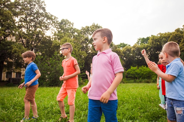 Grupa szczęśliwych dzieci grających w gry na zielonym polu na świeżym powietrzu w okresie letnim