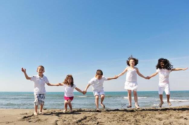 grupa szczęśliwych dzieci na plaży, które bawią się i grają w gry