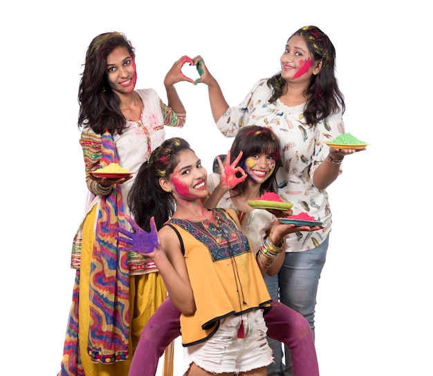 Grupa szczęśliwych młodych dziewcząt, zabawy z kolorowym proszkiem na festiwalu kolorów Holi