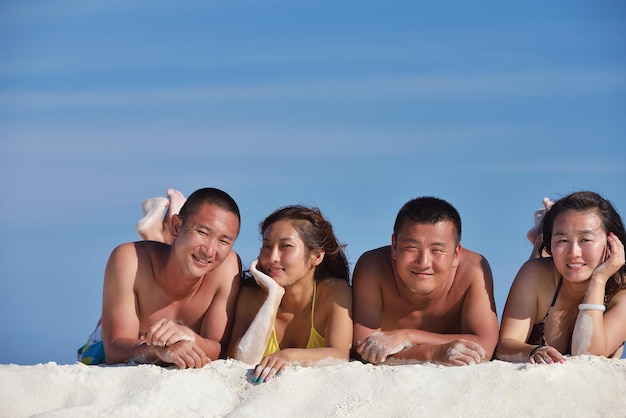 Grupa szczęśliwych młodych ludzi bawi się i cieszy na białej piaszczystej plaży w piękny letni dzień