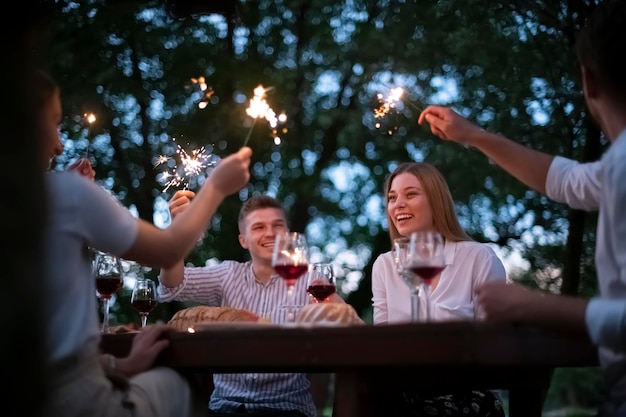 grupa szczęśliwych przyjaciół na pikniku francuska kolacja na świeżym powietrzu podczas letnich wakacji w pobliżu rzeki w pięknej przyrodzie