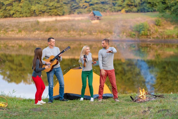 Grupa Szczęśliwych Przyjaciół Z Gitarą, Zabawy Na świeżym Powietrzu, Tańca I Skakania W Pobliżu Jeziora W Parku