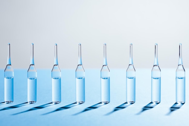 Grupa szklanych ampułek stojących w rzędzie na niebieskim tle