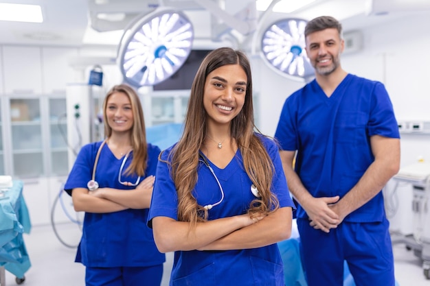 Grupa trzech lekarzy i pielęgniarek stojących w szpitalnym korytarzu w fartuchach Zespół pracowników służby zdrowia wpatruje się w kamerę i uśmiecha się