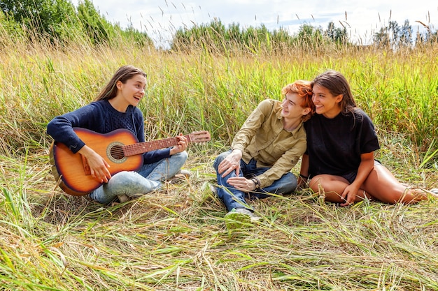 Grupa Trzech Przyjaciół Chłopca I Dwóch Dziewczyn Z Gitara śpiewa Piosenkę, Zabawy Razem Na świeżym Powietrzu