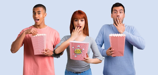 Grupa trzech przyjaciół jedzenie popcorns