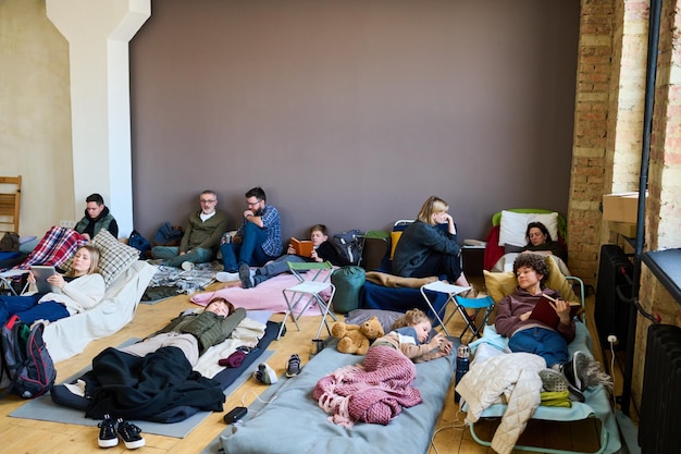 Grupa Uchodźców Korzystających Z Mobilnych Gadżetów Rozmawiających I śpiących Na Kuszetkach