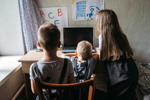 Grupa Uczniów Lub Przyjaciół W Słuchawkach Siedzących W Pobliżu Laptopa W Domu Rodzinny Uczeń Szkoły