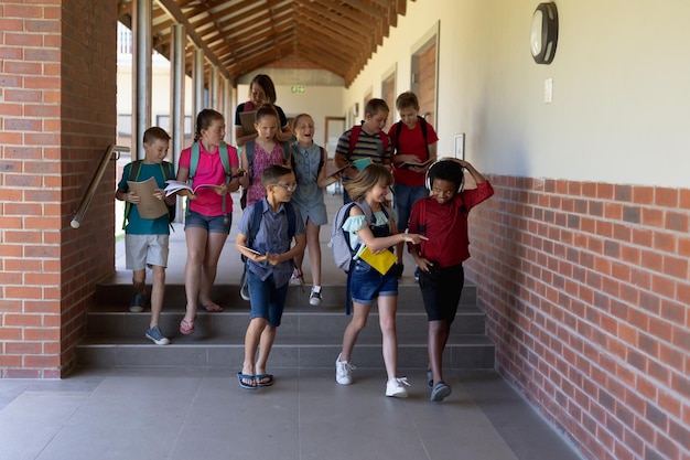 grupa uczniów spacerujących korytarzem na świeżym powietrzu w szkole podstawowej