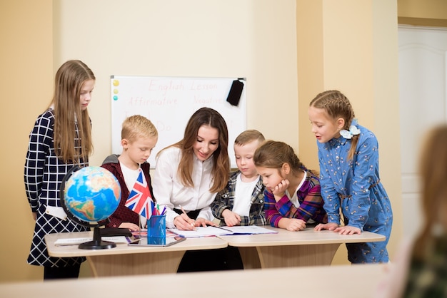 Zdjęcie grupa uczniów szkół podstawowych i nauczycieli pracujących przy biurkach w klasie.