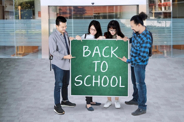 Grupa uczniów z powrotem do szkoły pisząc na zielonej tablicy