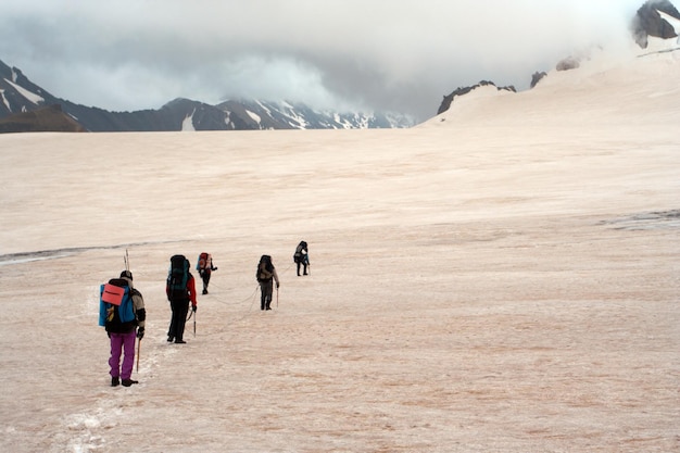 Grupa wędrowców zabezpieczona liną spacerująca po ośnieżonym lodowisku