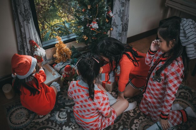 Grupa wesołych dzieci pomaga udekorować choinkę na Boże Narodzenie Wesołych Świąt i wesołych świąt