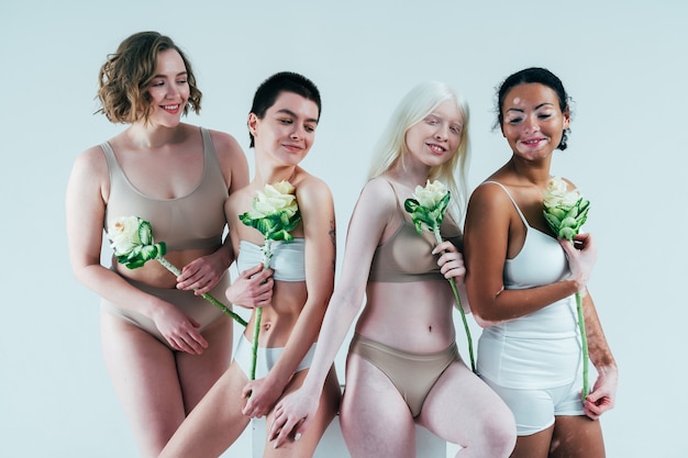 Grupa wieloetnicznych kobiet z różnym rodzajem skóry pozujących razem w studio Pojęcie o ciele