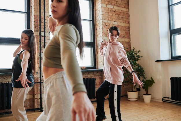 Zdjęcie grupa współczesnych nastolatków w odzieży sportowej ćwiczących ruchy taneczne