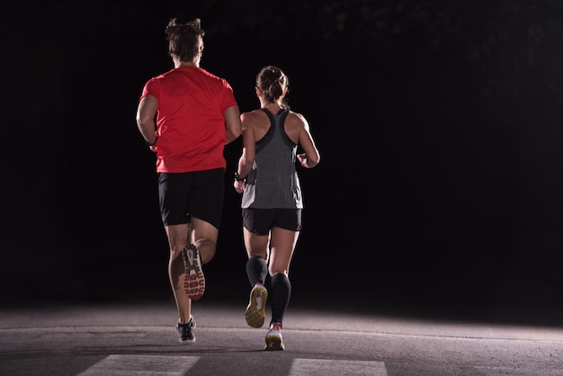 Grupa zdrowych ludzi jogging w parku miejskim, zespół biegaczy w nocy szkolenia