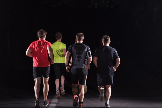 Grupa zdrowych ludzi jogging w parku miejskim, zespół biegaczy w nocy szkolenia