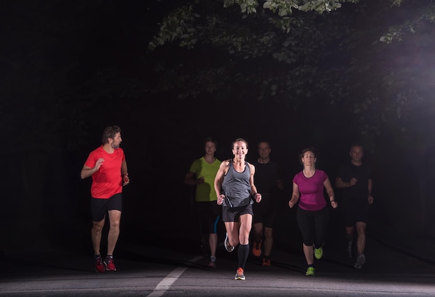 Grupa zdrowych ludzi jogging w parku miejskim, zespół biegaczy w nocy szkolenia