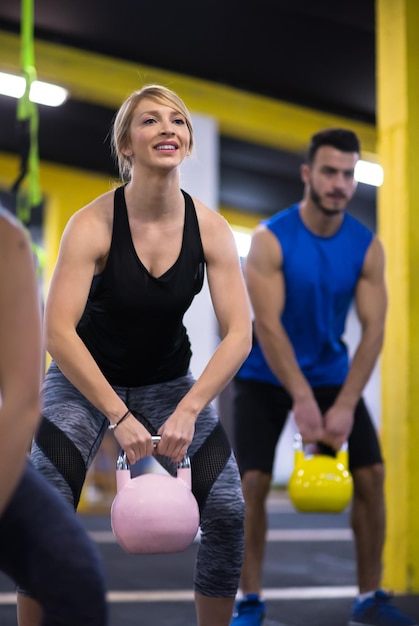 Grupa zdrowych młodych sportowców robienie ćwiczeń z kettlebells w fitness cross studio