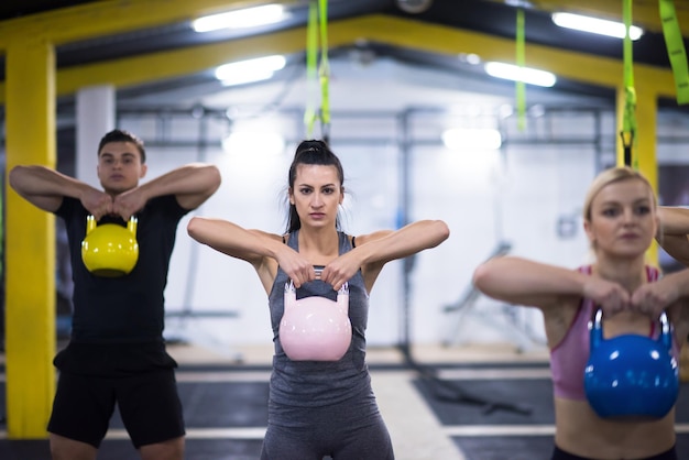 Grupa zdrowych młodych sportowców robienie ćwiczeń z kettlebells w fitness cross studio