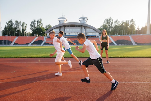 Grupę dzieci chłopców uczy trener na starcie przed bieganiem na stadion o zachodzie słońca Zdrowy styl życia