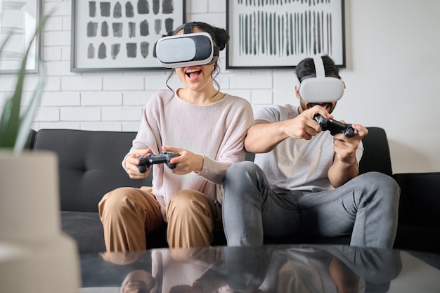 Gry VR i metaverse z parą grającą razem w gry wideo w domu dla zabawy lub przyjemności Gra w rzeczywistości wirtualnej i sztuczna inteligencja 3D z mężczyzną i kobietą, którzy łączą się w salonie