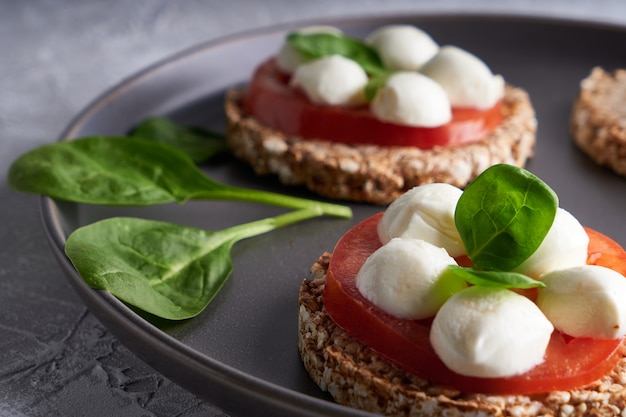 Grzanki z mozzarellą, pomidorami i szpinakiem w szarym talerzu