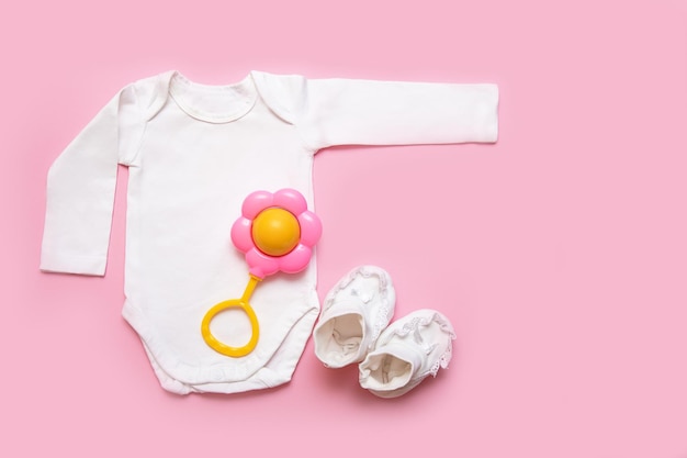 Grzechotka do body i buciki dla noworodka na różowym tle