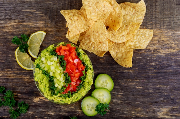 Guacamole z chipsami kukurydzianymi na rustykalnym drewnianym stole