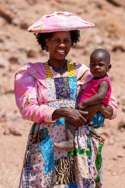 Guerrero kobieta w kolorowej tradycyjnej sukience z dzieckiem w ramionach Namibia