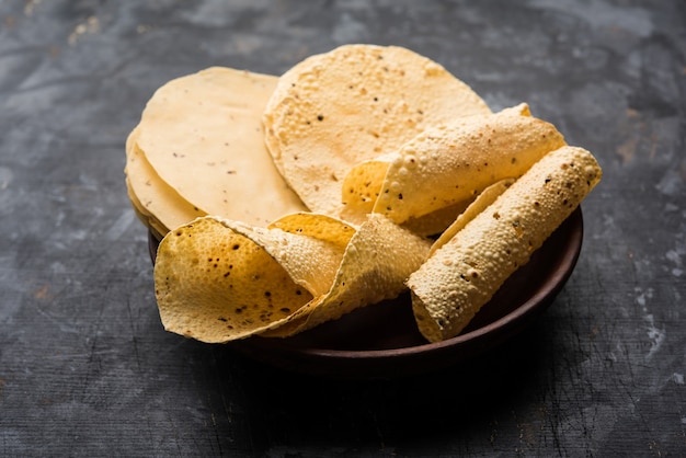 Gujarati papad lub papadum w postaci surowej suszonej z pieczonym rożkiem, bułką i odmianą płaską