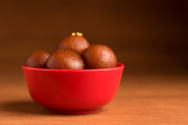 Gulab Jamun w czerwonej misce na drewnianym. Indyjski deser lub słodkie danie.