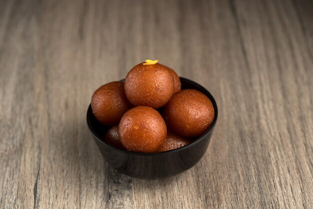 Gulab Jamun w misce na podłoże drewniane.