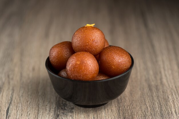 Gulab Jamun w misce na podłoże drewniane.