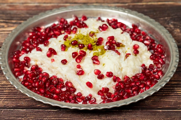 Gullac deser Ramadan deser Gullac ozdobiony granatem i pistacją na miedzianej płytce na drewnianym tle Symboliczne jedzenie