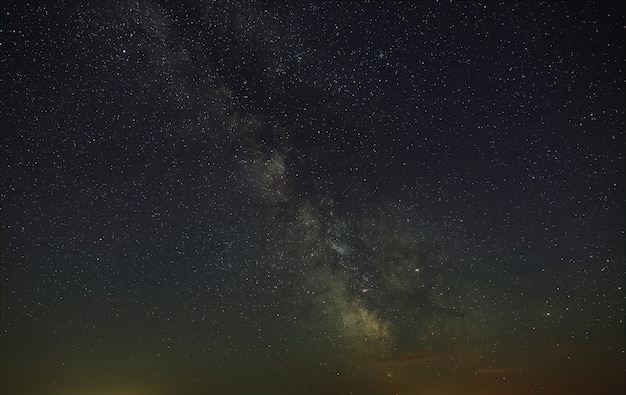 Gwiaździste nocne niebo z Drogą Mleczną. Astrofotografia przestrzeni otwartej.