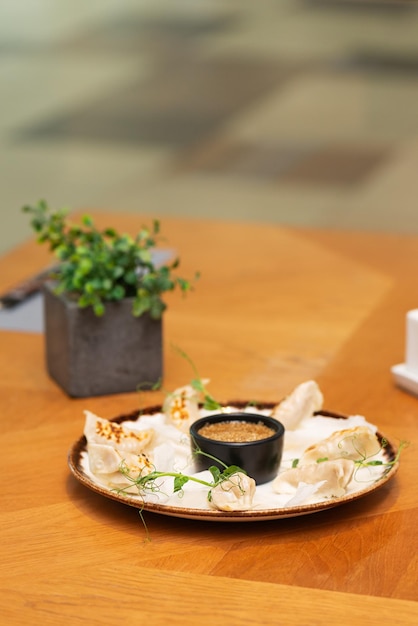 Gyoza lub japońskie smażone knedle z sosem na talerzu w restauracji Orientacja pionowa ciężkie światło